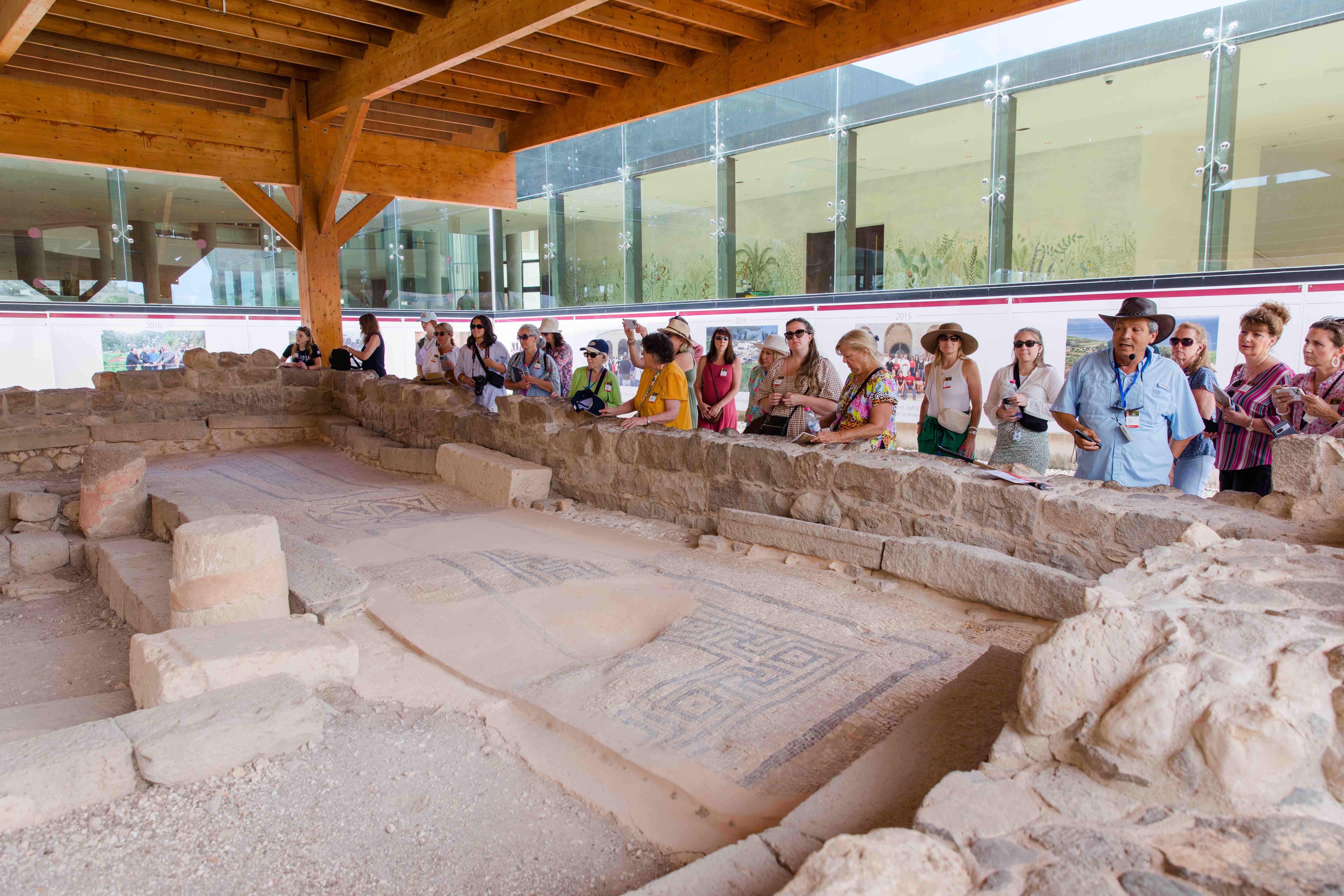 A group of tourists learn about Magdala from a tour guide at the archaeological site