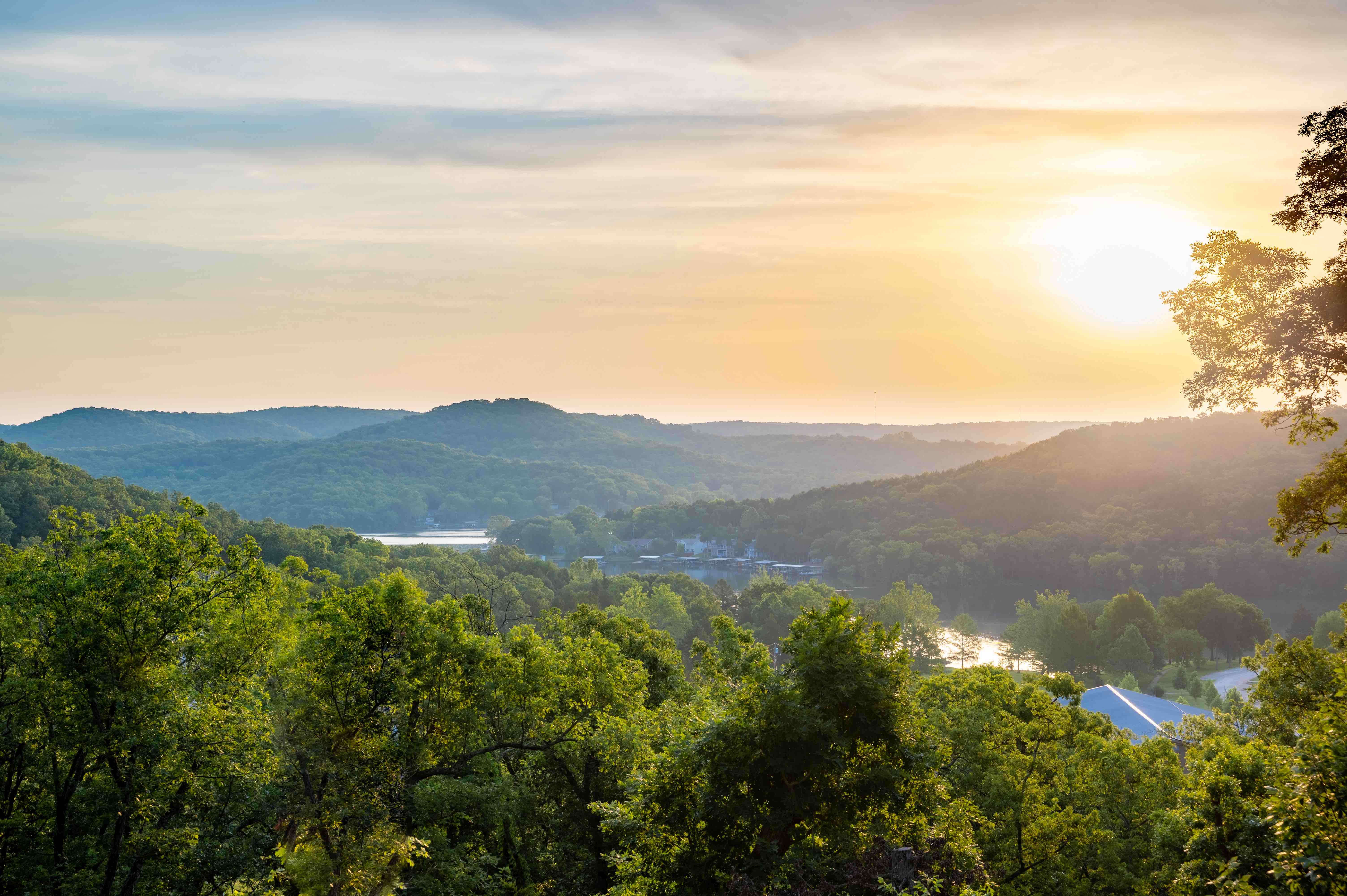Sun rising over the green hills and blue lake of Ozark, Missouri