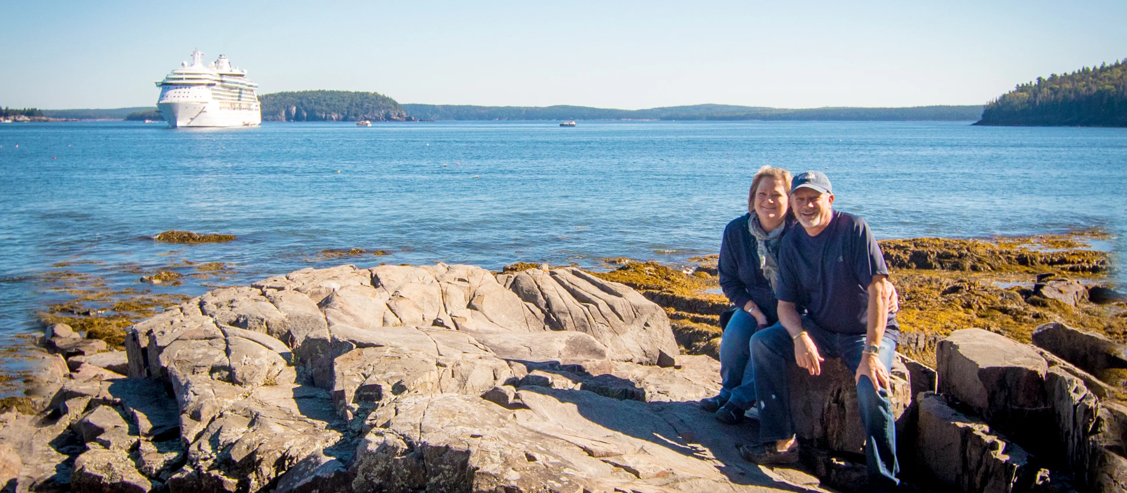 A couple sitting together on the rocky shore of the ocean