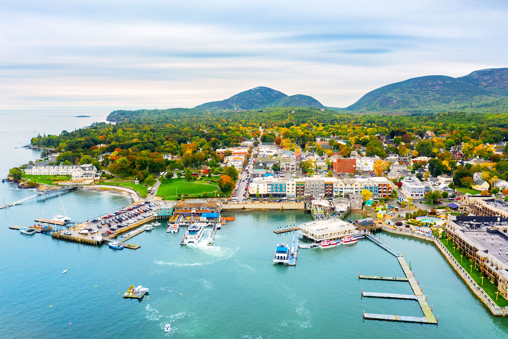 Aerial view of Bar Harbor with ships coming into dock, colonial-style buildings, and colorful trees dotting the town.