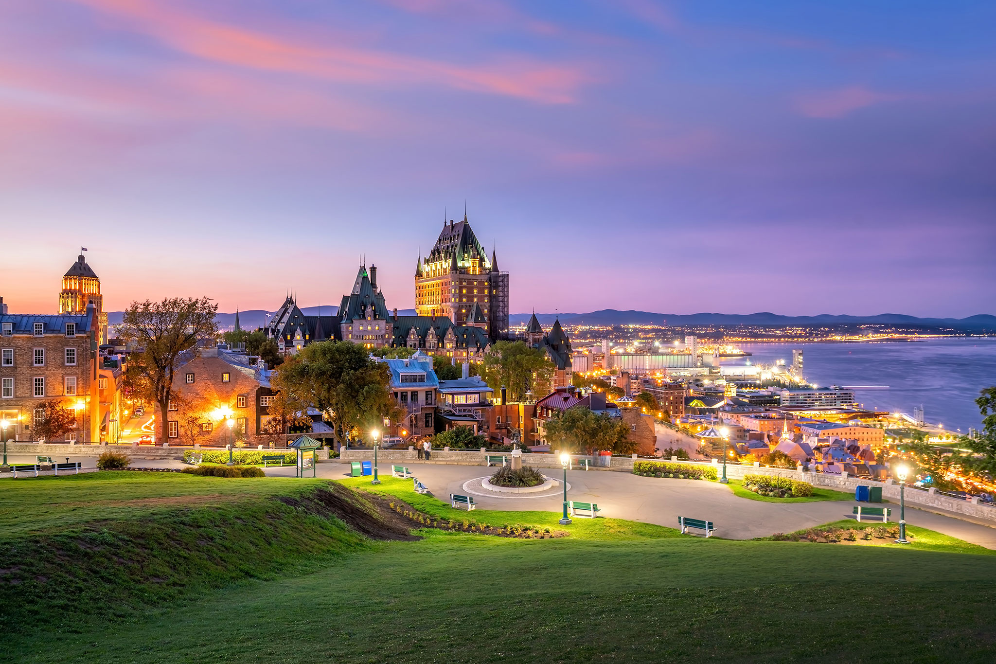 Panoramic view of the Québec City skyline during a soft lilac sunset with the Saint Lawrence River in the background.