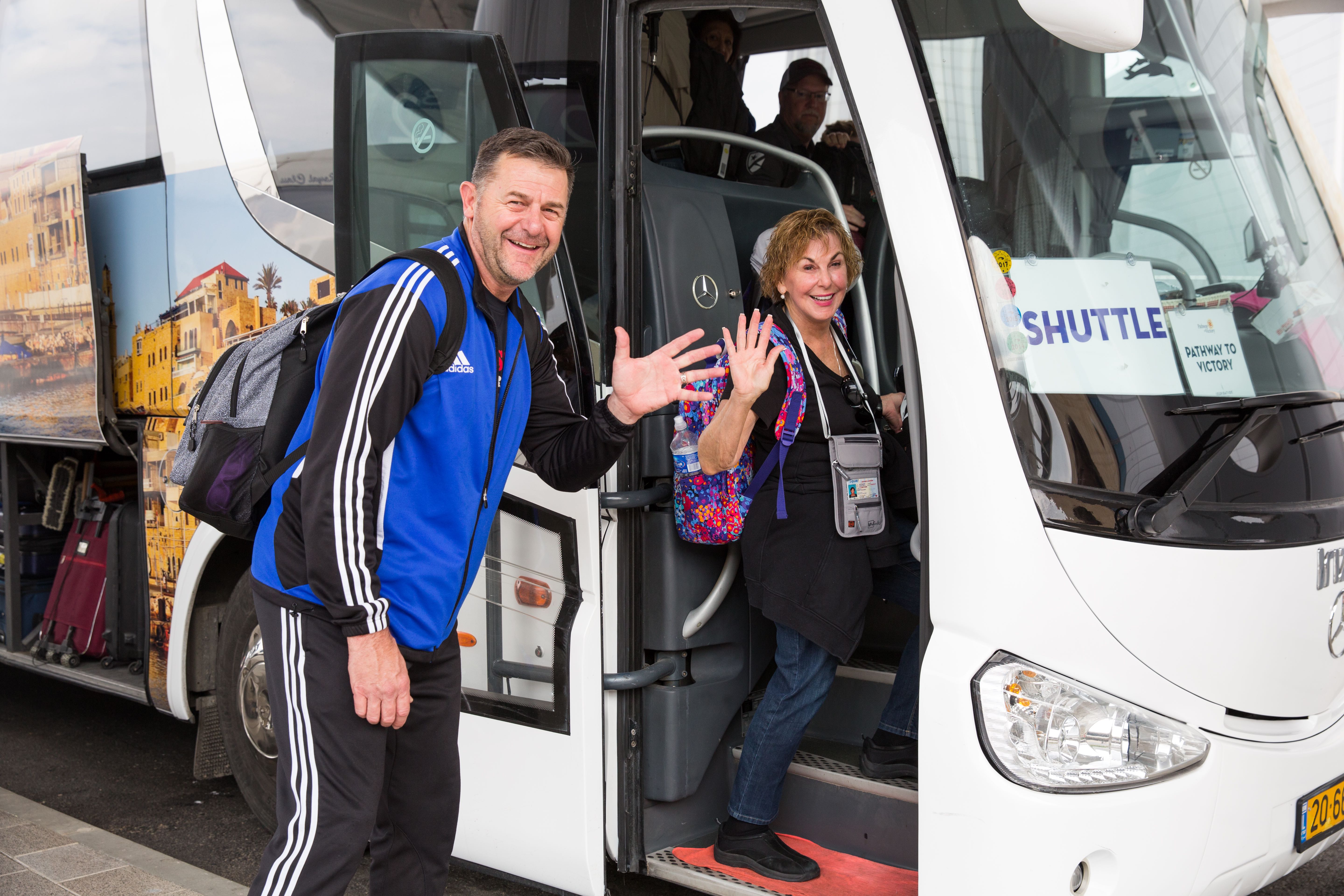 A couple of Israel travelers wave as they enter the airport shuttle bus