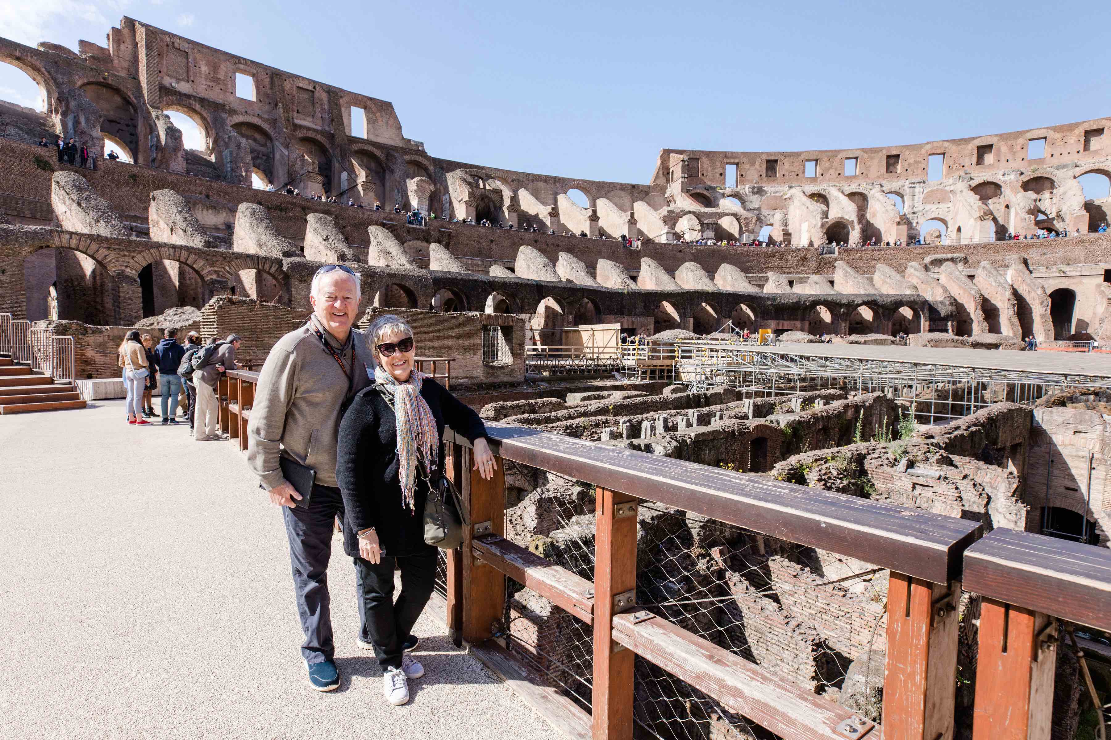 Christian travelers standing and smiling at the Colosseum in Rome, Italy
