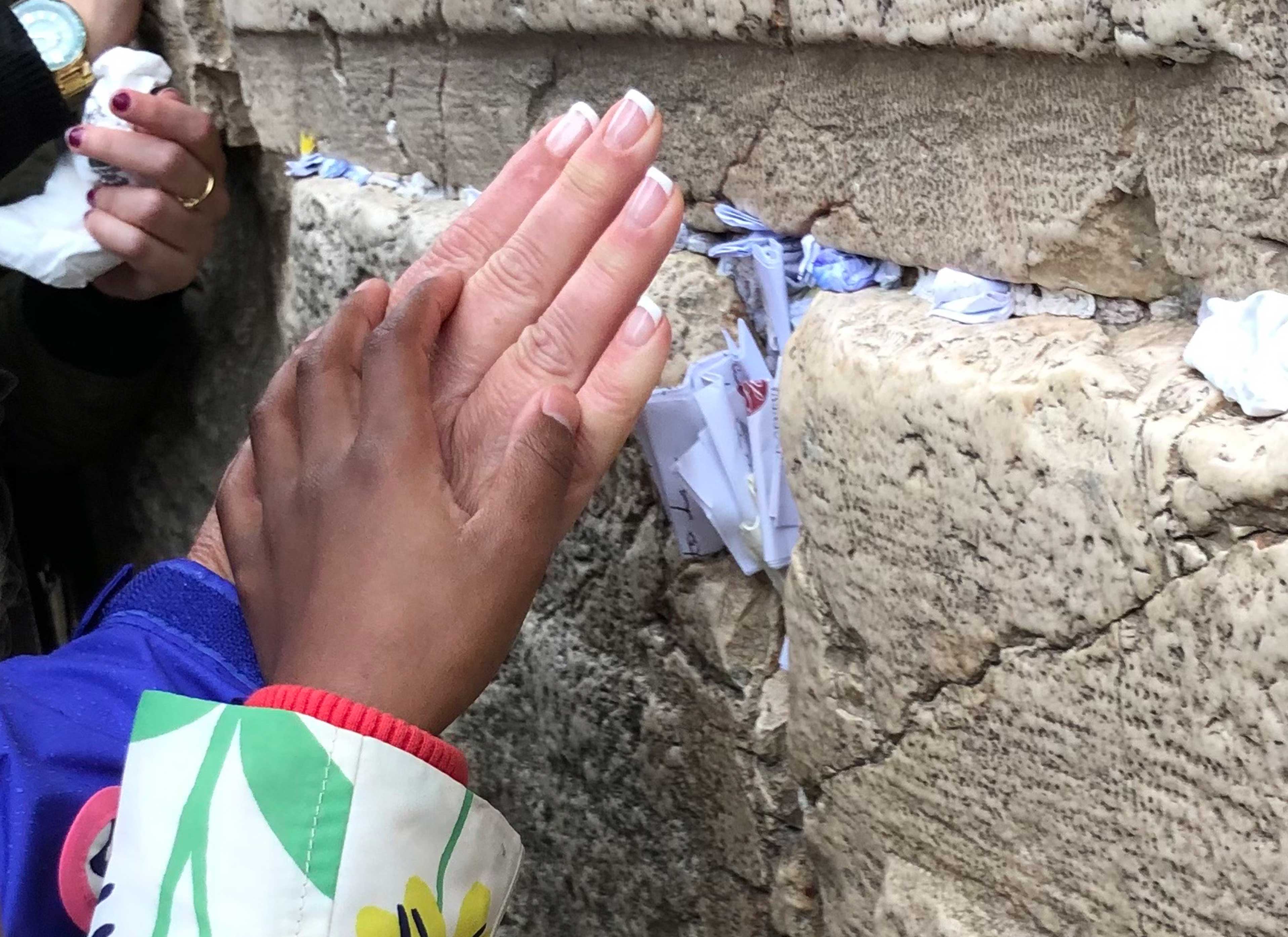 Lisa Harper’s hand and Missy’s hand placing the paper they wrote a prayer on in a crack in the Western Wall